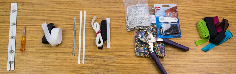Left to Right: Front closure or 'busk', awl, waist tape, steel bones in spiral and flat sprung steel, bone casing, eyelets and eyelet setter, bias binding.